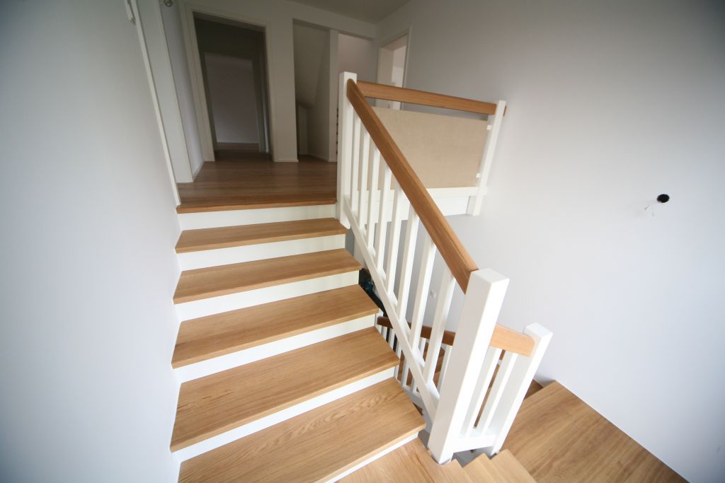 Modernisierte Treppe mit Holzstufen und weißem Geländer